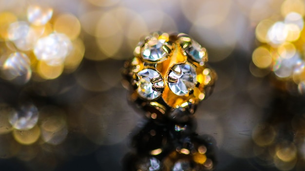 Close up of Single Golden Diamond Bead for Necklace with colorful bokeh background