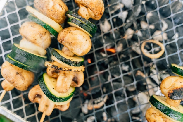 Close up of single use grill for outdoors picnic with vegetables on wooden stick