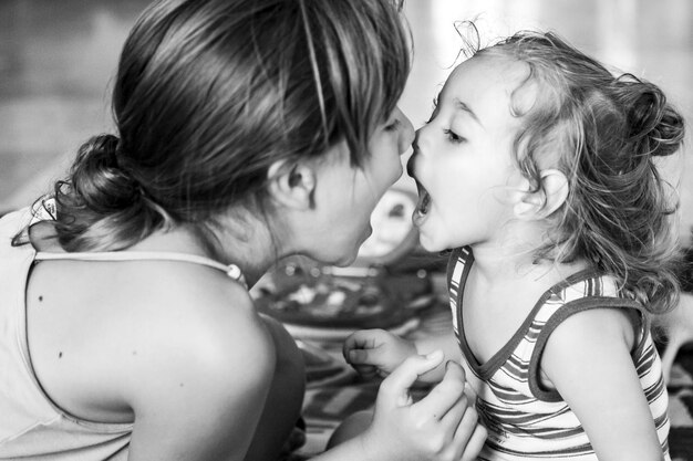 Close-up of sisters with mouth open at home