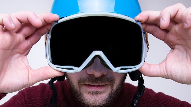 Foto primo piano del volto di uno sciatore con occhiali e casco