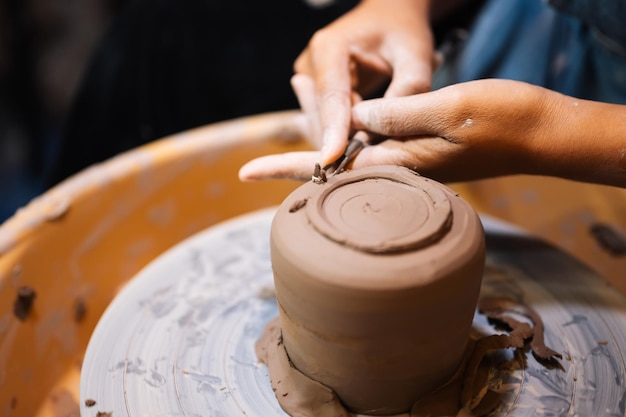 Photo close up on skillful hands sculpting pottery jar on potter wheel