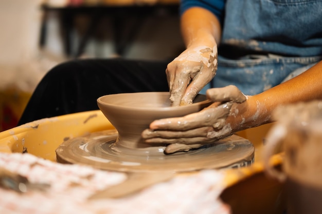 Close up on skillful hands sculpting pottery jar on potter wheel