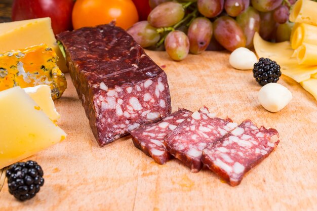 Close Up of Sliced Cured Meat on Gourmet Cheese Board with Variety of Cheeses and Garnished with Fruit