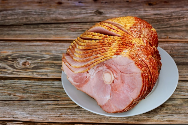 Close up of sliced honey smoked ham on wooden table. Copy space.