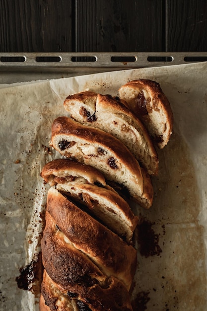 Foto un primo piano di pane intrecciato a fette di ricotta dolce con uvetta e marmellata. colpo dall'alto.