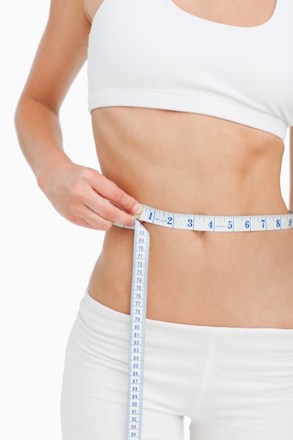 Photo close-up of a slim woman measuring her waist