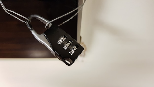 Close-up small combination lock closes electrical panel with\
black glass cover in office building corridor.