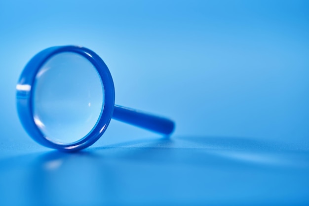 Close up of small magnifying glass on blue background