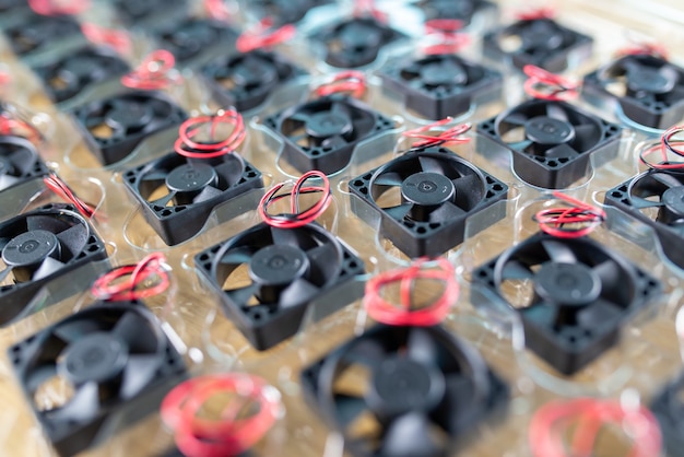 Close-up small plastic computer coolers with wires lie in transparent plastic package on a wooden table in the manufacture of computers. Computer and equipment factory concept