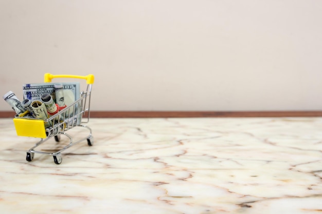 Close-up of small shopping cart with paper currencies on floor