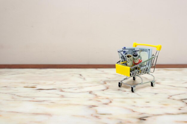 Close-up of small shopping cart with paper currencies on floor