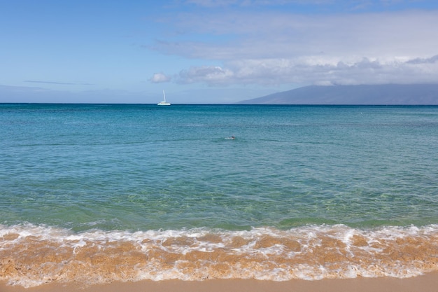 熱帯のビーチの砂の上の小さな波のクローズアップ海の水の背景