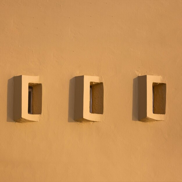 Photo close-up of small windows on yellow wall