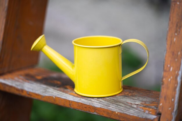 Close up of a small yellow watering can in the garden