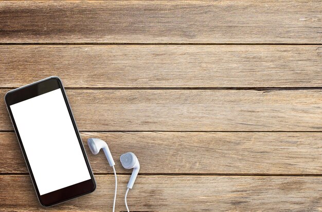 Close up smart phone and white ear phone on brown old wood background