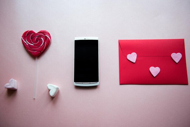 Photo close-up of smart phone with red envelope and lollipop on table