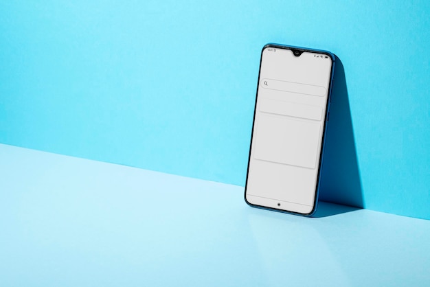 青い壁の反対側のテーブル上のスマートフォンのクローズアップ