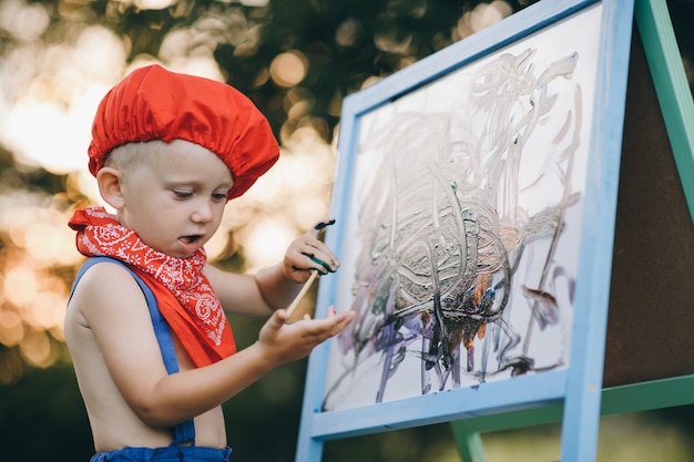 Close up of smile painter man. The hands of the artist's boy, who paints an oil painting on the nature