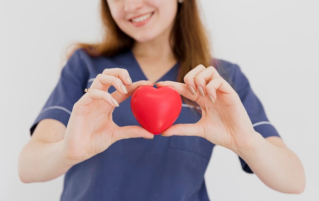 Photo close-up smiley doctor holding heart shaped toy