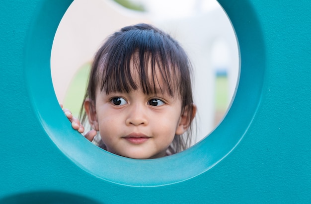 Foto chiuda sul fronte di smiley della bambina asiatica sveglia nel campo da giuoco