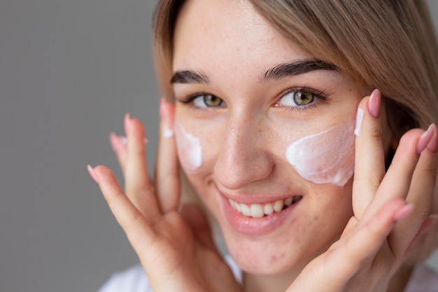 close up smiley woman usign face cream