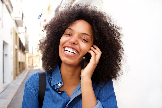 Chiuda sulla donna afroamericana sorridente che parla sullo smart phone