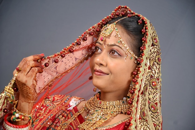 Close-up of smiling bride in traditional clothing over gray background