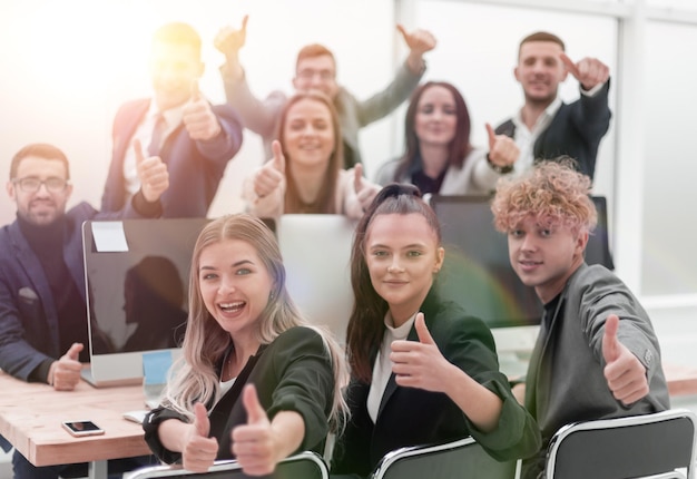 close up. smiling business team sitting at a Desk and showing thumbs up. the concept of teamwork