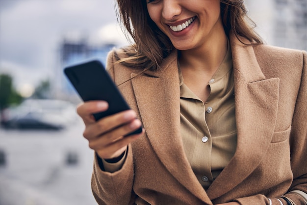 Foto primo piano su una sorridente donna d'affari caucasica che legge un messaggio di testo sul suo gadget