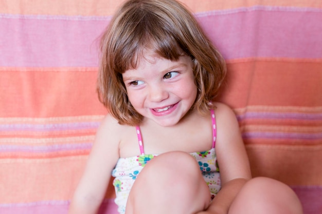 Close-up of smiling girl looking away while sitting on sofa