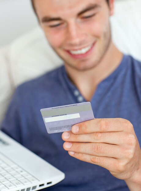 Primo piano di un uomo sorridente che tiene una carta e un computer portatile