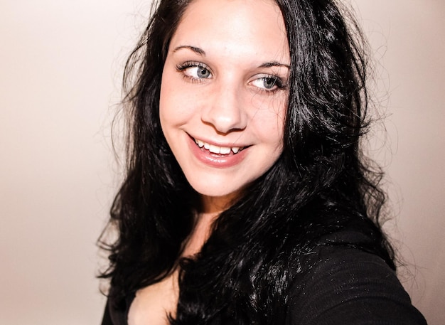 close-up of smiling woman against wall