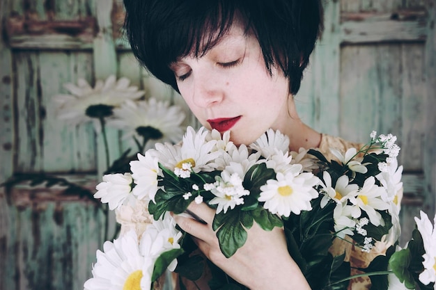 Photo close-up of smiling woman embracing flowers