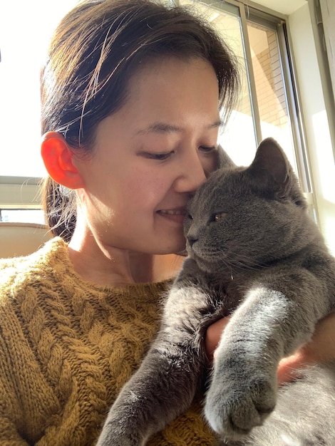 家で猫にキスする笑顔の女性のクローズアップ