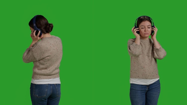Photo close up of smiling woman listening to music online, using headphones to enjoy song on radio. young adult standing over greenscreen backdrop and having fun with mp3 sounds, wireless headset.