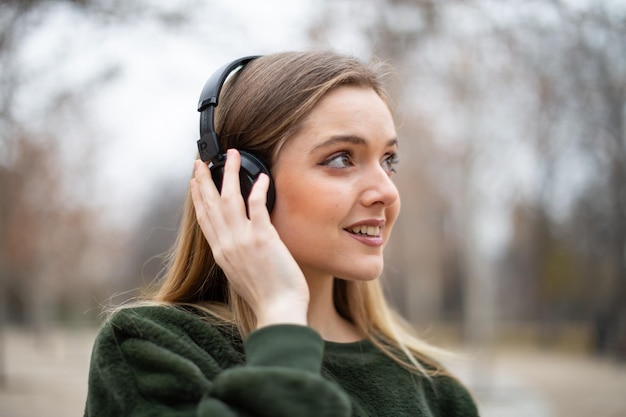 Foto close-up di una donna sorridente che ascolta la musica mentre guarda da un'altra parte