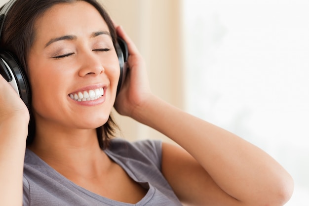 Close up of smiling woman sitting on sofa with earphones and eyes closed