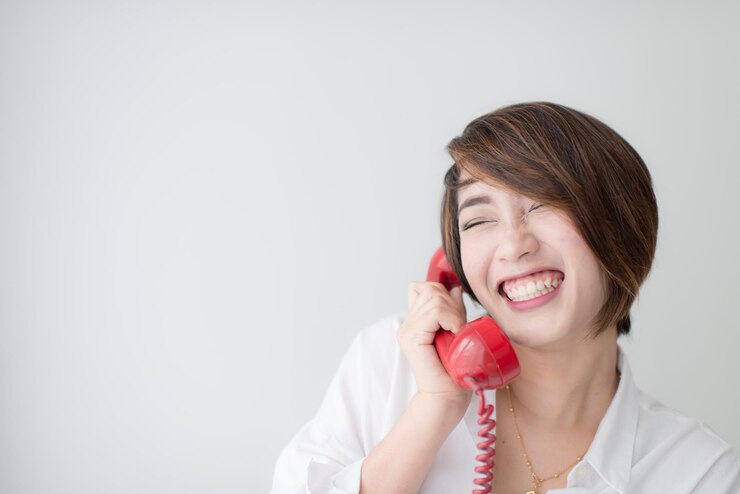 Photo 壁に向かって電話で話している笑顔の女性のクローズアップ