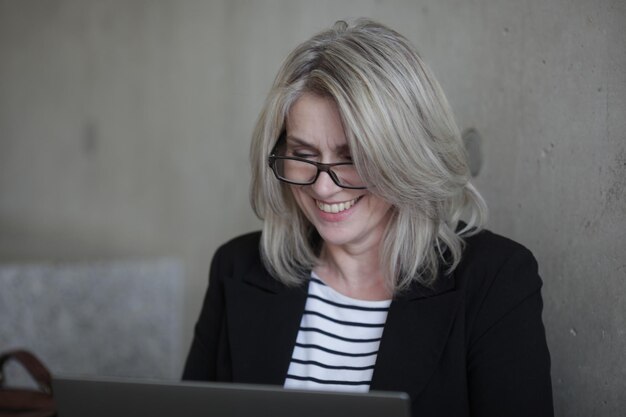 Photo close-up of smiling woman using laptop in office