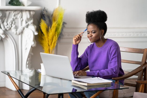 Photo close-up of smiling woman using laptop sitting on chair at home