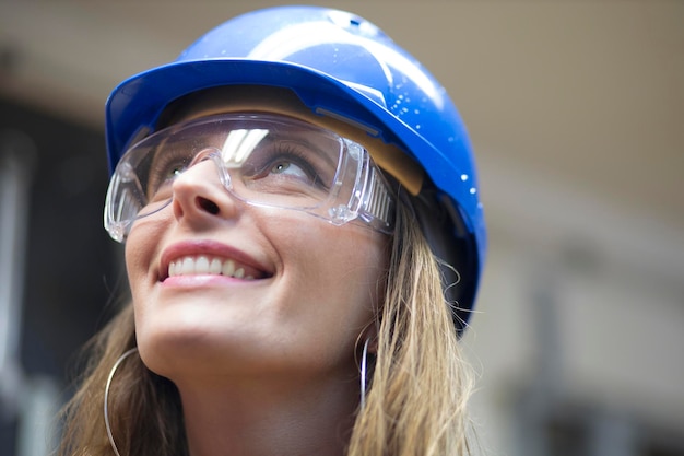 Photo close-up of smiling woman wearing hardhat looking up