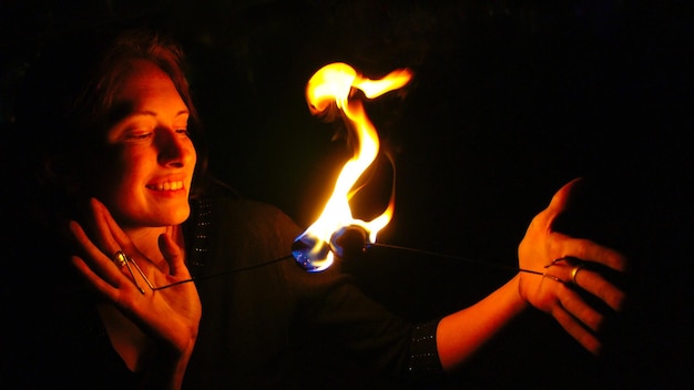 Foto close-up di una donna sorridente con un fuoco che brucia di notte