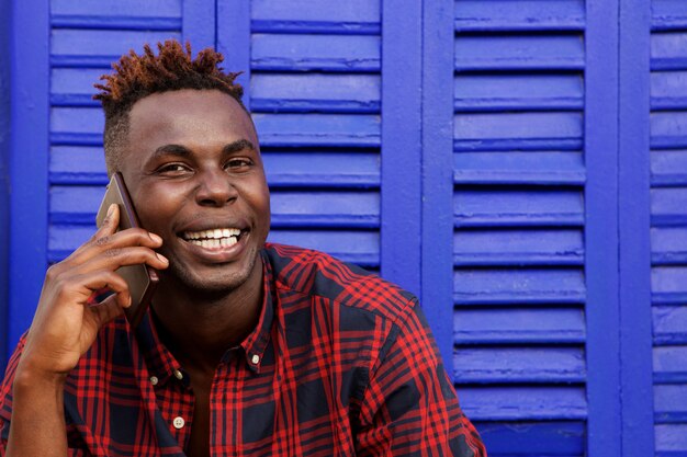 Close up smiling young afro american can man using mobile phone