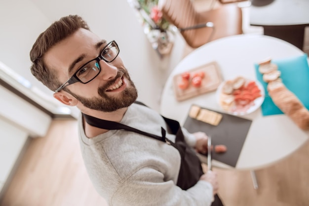 写真 サラミをスライスする笑顔の若い男をクローズアップ