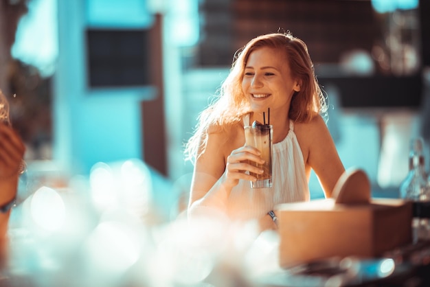 笑顔の若い女性が飲み物を飲んでいるクローズアップ