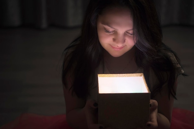 close-up of smiling young woman holding illuminated box