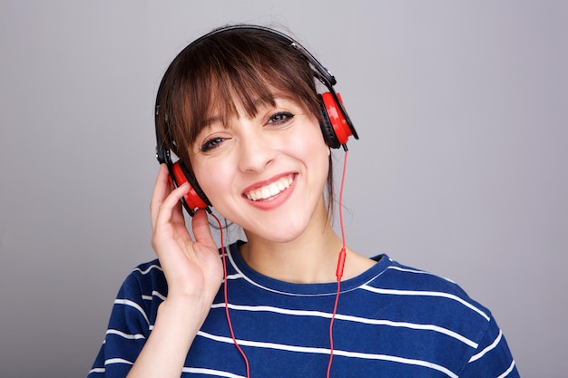 Close up smiling young woman listening to music with headphones