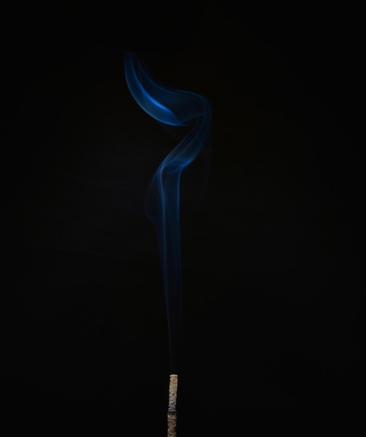 Close-up of smoke emitting from incense against black background