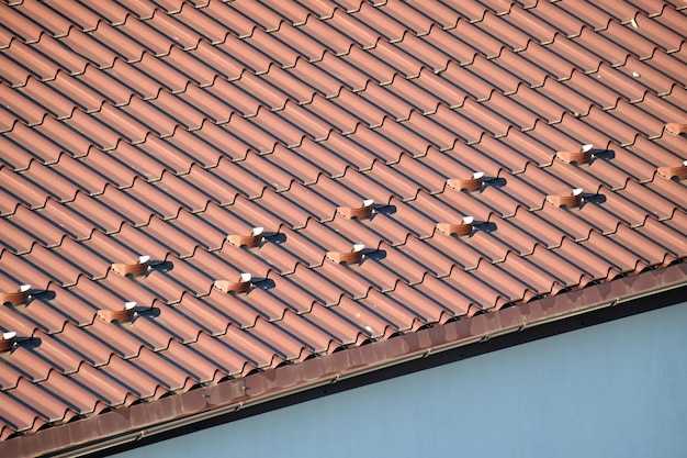 Close-up sneeuwwacht voor veiligheid in de winter op het dak van het huis bedekt met stalen dakspanen. Betegelde bekleding van het gebouw.