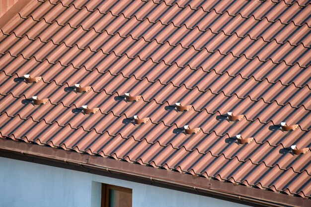 Close-up sneeuwwacht voor veiligheid in de winter op het dak van het huis bedekt met stalen dakspanen. Betegelde bekleding van het gebouw.